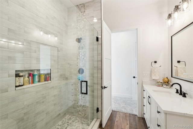 bathroom with a shower with shower door, vanity, and wood-type flooring