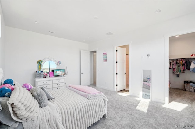 bedroom with light colored carpet, connected bathroom, a closet, and a walk in closet