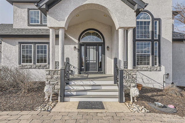 doorway to property featuring a shingled roof and stucco siding