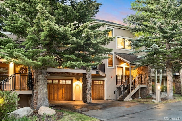 view of front of house with roof with shingles, stairway, and stucco siding