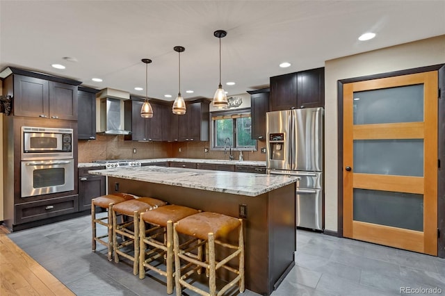 kitchen featuring a kitchen island, wood-type flooring, stainless steel appliances, and wall chimney exhaust hood