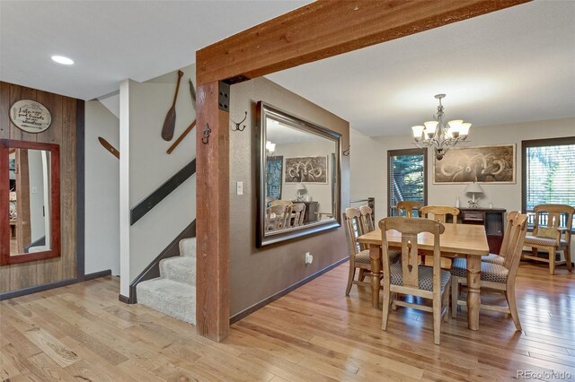 dining space with wooden walls, a notable chandelier, and light hardwood / wood-style floors