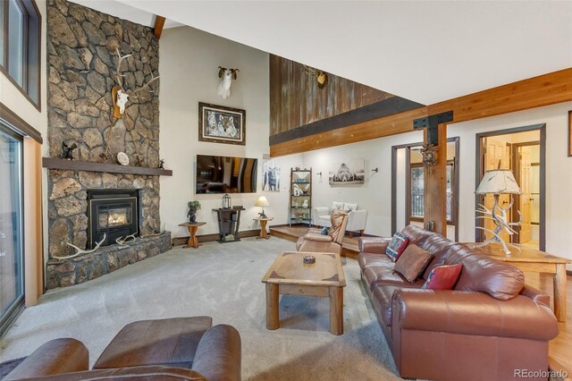 carpeted living room with a stone fireplace and a towering ceiling