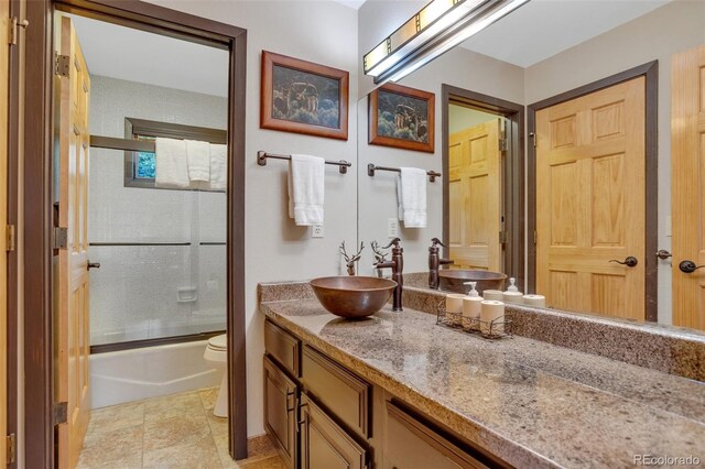 full bathroom with vanity, tile patterned floors, combined bath / shower with glass door, and toilet