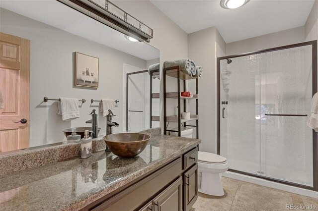 bathroom with tile patterned floors, toilet, vanity, and an enclosed shower