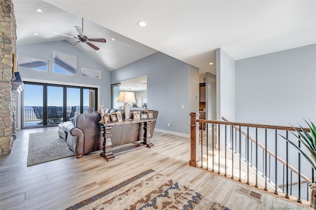 living room with ceiling fan, vaulted ceiling, and light hardwood / wood-style flooring