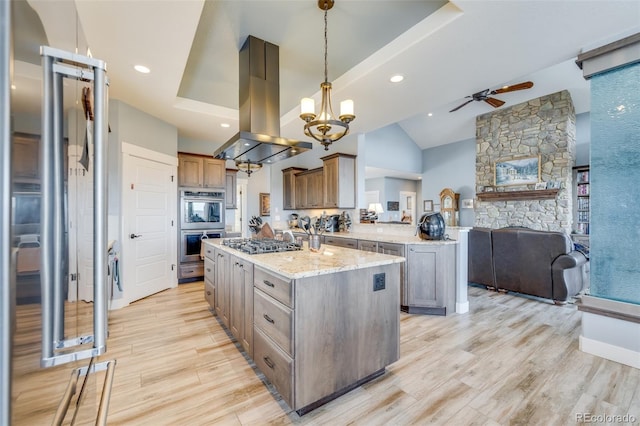 kitchen featuring decorative light fixtures, island range hood, a kitchen island with sink, and stainless steel gas stovetop