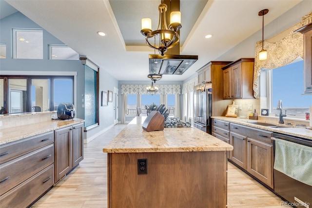 kitchen featuring sink, hanging light fixtures, a chandelier, a kitchen island, and appliances with stainless steel finishes