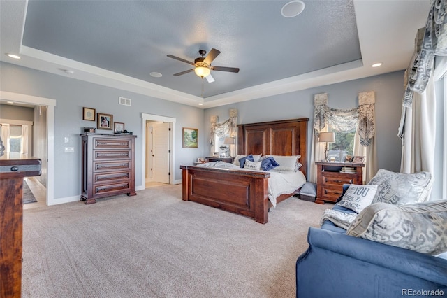 carpeted bedroom with a textured ceiling, a tray ceiling, and ceiling fan