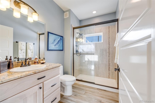 bathroom featuring hardwood / wood-style floors, vanity, toilet, and a shower with shower door