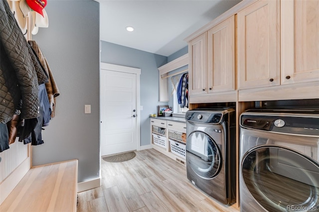 laundry room with washer and dryer, cabinets, and light wood-type flooring