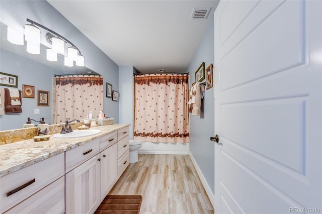 full bathroom with hardwood / wood-style floors, vanity, toilet, and shower / bath combo with shower curtain