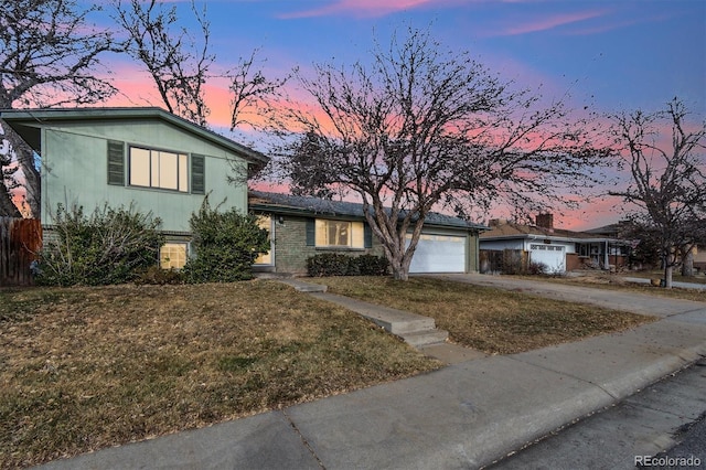 tri-level home with a garage and a lawn