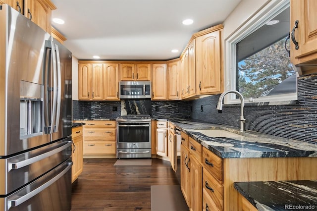 kitchen with dark stone countertops, appliances with stainless steel finishes, dark hardwood / wood-style flooring, decorative backsplash, and sink