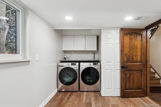 washroom featuring cabinets, washer and clothes dryer, and hardwood / wood-style floors