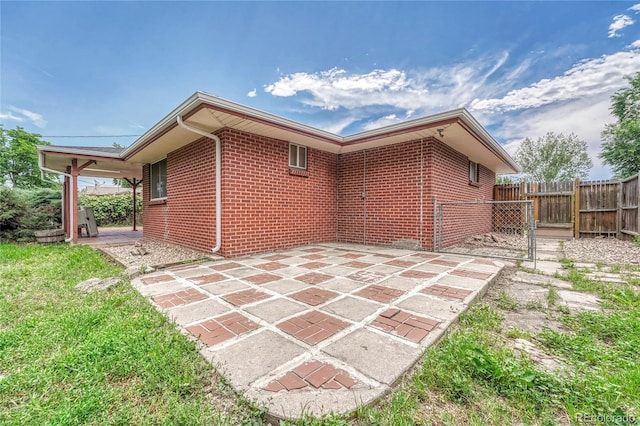 3463 W Bowles Ave, Littleton, CO 80123 - rear view of house featuring brick siding, a patio area, and a gate