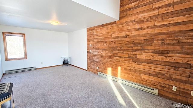 carpeted empty room featuring a baseboard heating unit and wooden walls