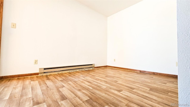 empty room with wood-type flooring, a baseboard heating unit, and vaulted ceiling