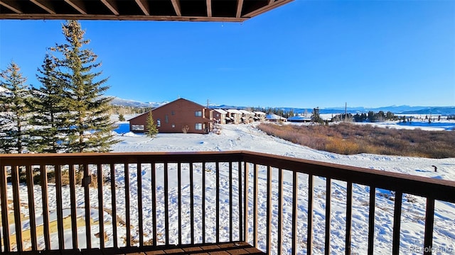 snow covered back of property featuring a mountain view