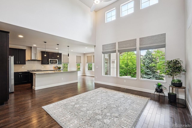 2264 S Joyce St, Lakewood, CO 80228 - kitchen with appliances with stainless steel finishes, wall chimney exhaust hood, open floor plan, a towering ceiling, and dark wood finished floors