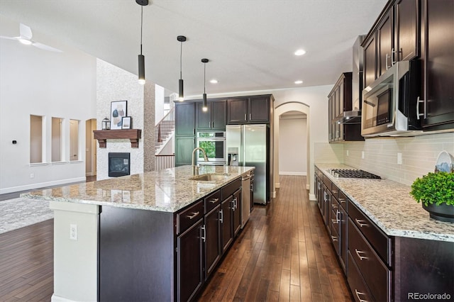 2264 S Joyce St, Lakewood, CO 80228 - kitchen featuring a sink, stainless steel appliances, dark wood finished floors, dark brown cabinetry, and a large fireplace