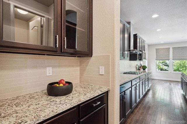 2264 S Joyce St, Lakewood, CO 80228 - kitchen with decorative backsplash, dark brown cabinetry, light stone countertops, glass insert cabinets, and dark wood-style flooring