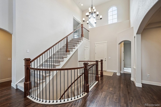 2264 S Joyce St, Lakewood, CO 80228 - staircase featuring arched walkways, hardwood / wood-style flooring, baseboards, a high ceiling, and a chandelier
