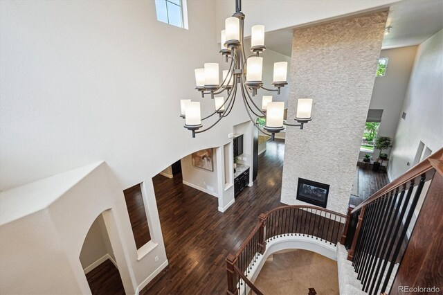 2264 S Joyce St, Lakewood, CO 80228 - stairway featuring a towering ceiling, wood finished floors, a chandelier, a large fireplace, and baseboards
