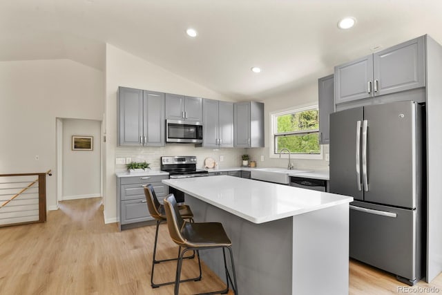 30221 Stagecoach Blvd, Evergreen, CO 80439 - kitchen featuring appliances with stainless steel finishes, gray cabinetry, vaulted ceiling, tasteful backsplash, and a center island