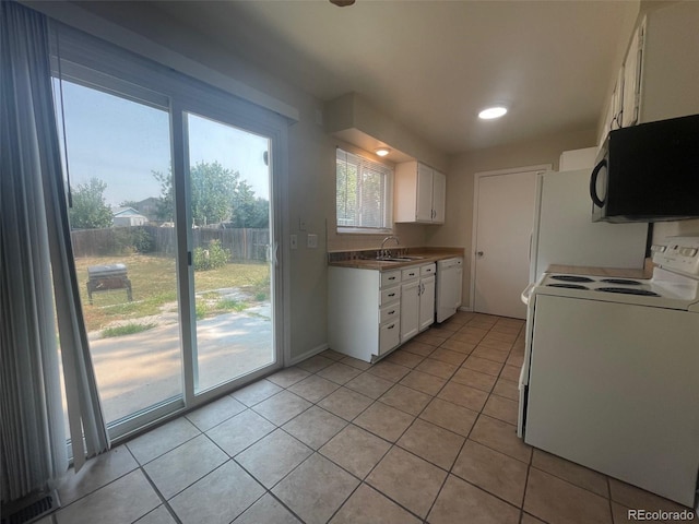 kitchen featuring sink, white appliances, white cabinetry, and light tile floors