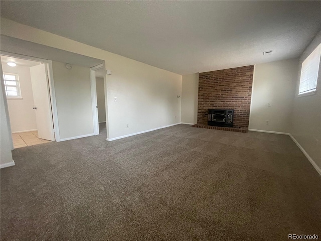 unfurnished living room with brick wall, light colored carpet, a textured ceiling, and a fireplace