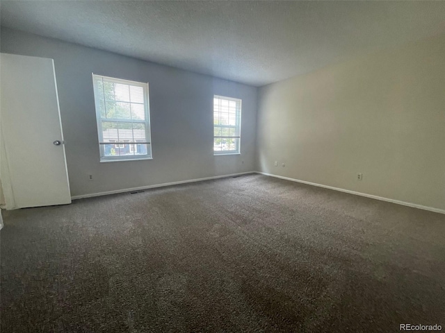 empty room with a textured ceiling and dark colored carpet