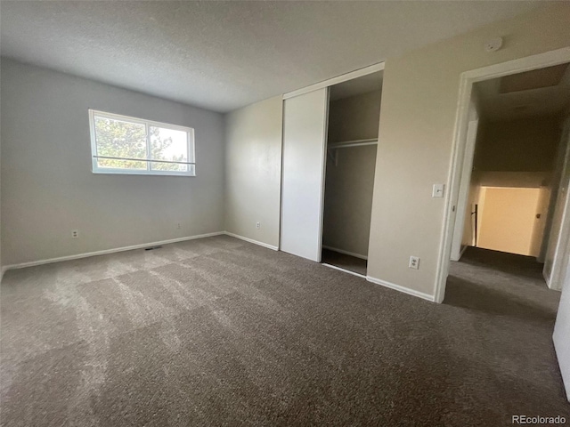 unfurnished bedroom with a textured ceiling and dark colored carpet