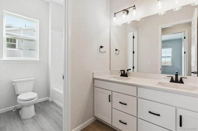 full bathroom with bathing tub / shower combination, vanity, hardwood / wood-style flooring, and toilet