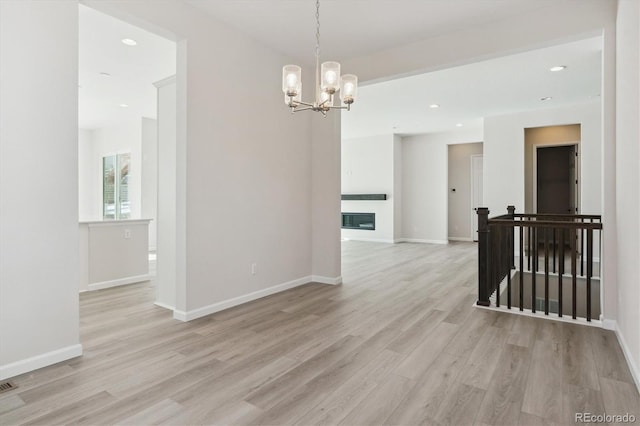 unfurnished room featuring light wood-type flooring and a chandelier