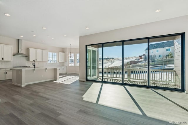 unfurnished living room with sink, a chandelier, and wood-type flooring