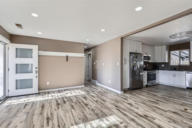 kitchen featuring appliances with stainless steel finishes, light hardwood / wood-style floors, white cabinetry, and sink