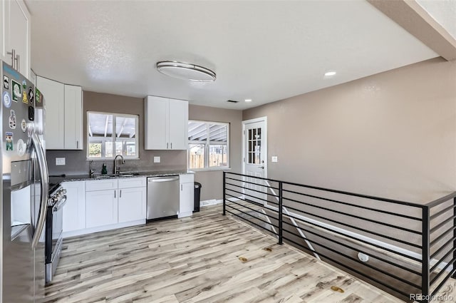 kitchen featuring white cabinets, sink, light wood-type flooring, and stainless steel appliances