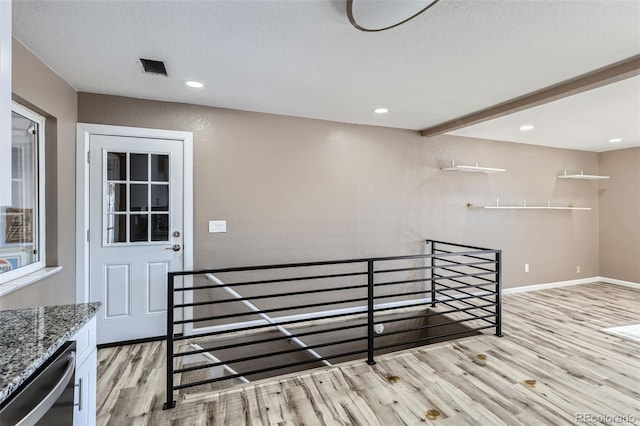 staircase with beamed ceiling, hardwood / wood-style floors, and a textured ceiling