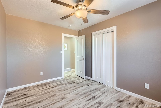 unfurnished bedroom featuring ceiling fan, a closet, and light wood-type flooring