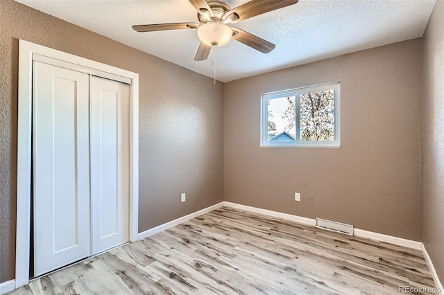 unfurnished bedroom featuring ceiling fan, light hardwood / wood-style floors, and a closet