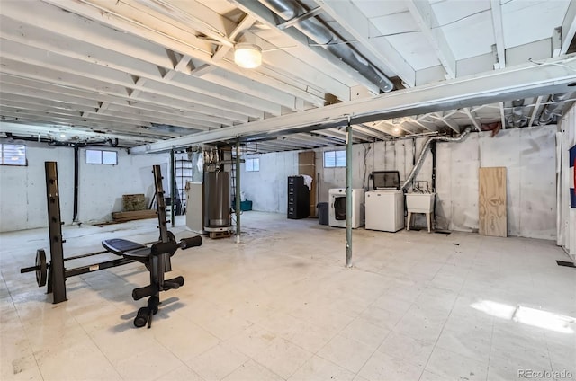 basement featuring water heater, washer and clothes dryer, a healthy amount of sunlight, and sink