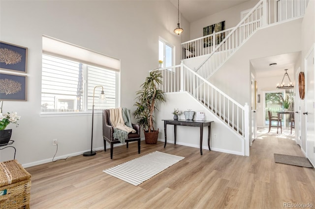 entryway with a notable chandelier, a towering ceiling, and light hardwood / wood-style flooring