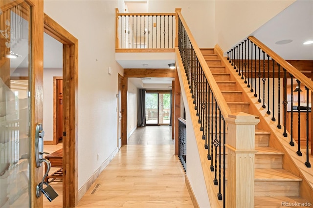 stairway with wood finished floors, baseboards, and a high ceiling