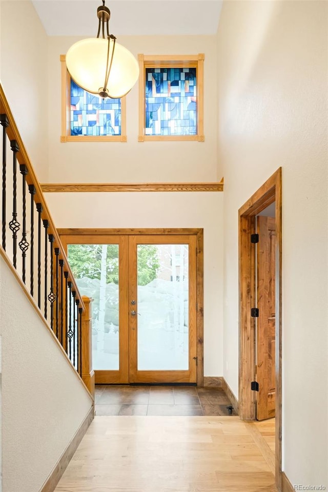 entrance foyer with stairs, baseboards, wood finished floors, a high ceiling, and french doors
