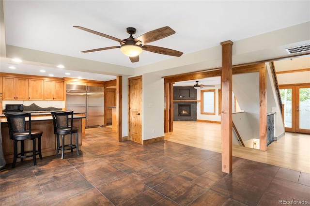 kitchen featuring built in fridge, ceiling fan, black microwave, recessed lighting, and a kitchen breakfast bar