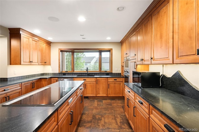 kitchen featuring a sink, black appliances, stone finish flooring, recessed lighting, and brown cabinetry