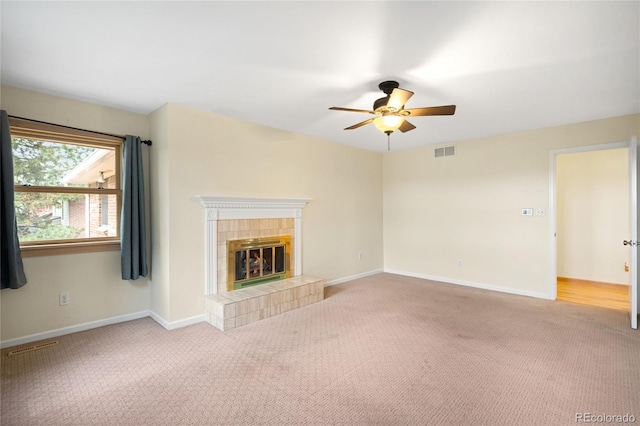 unfurnished living room featuring carpet, a ceiling fan, a tile fireplace, and baseboards