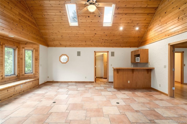 unfurnished living room with a ceiling fan, high vaulted ceiling, wooden ceiling, a skylight, and baseboards