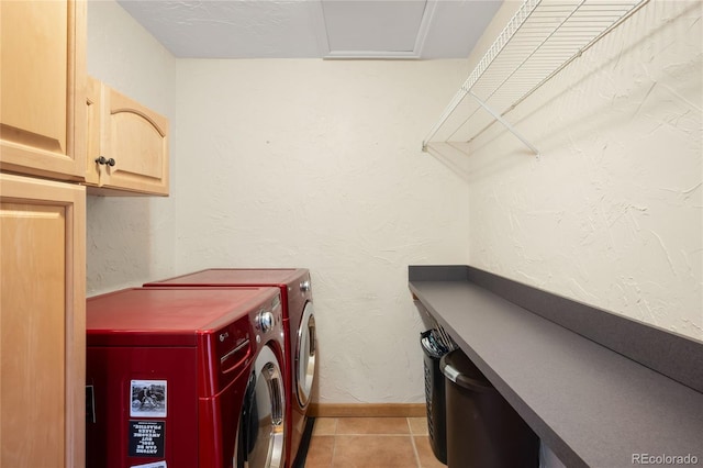 washroom featuring cabinet space, washing machine and dryer, baseboards, and light tile patterned floors